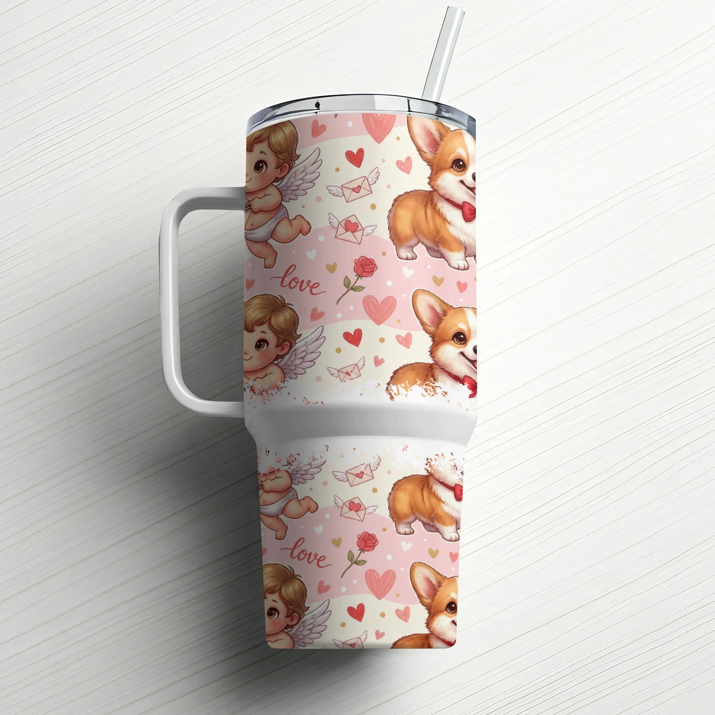 Tumbler with corgi and cupid graphics on a white wood background.