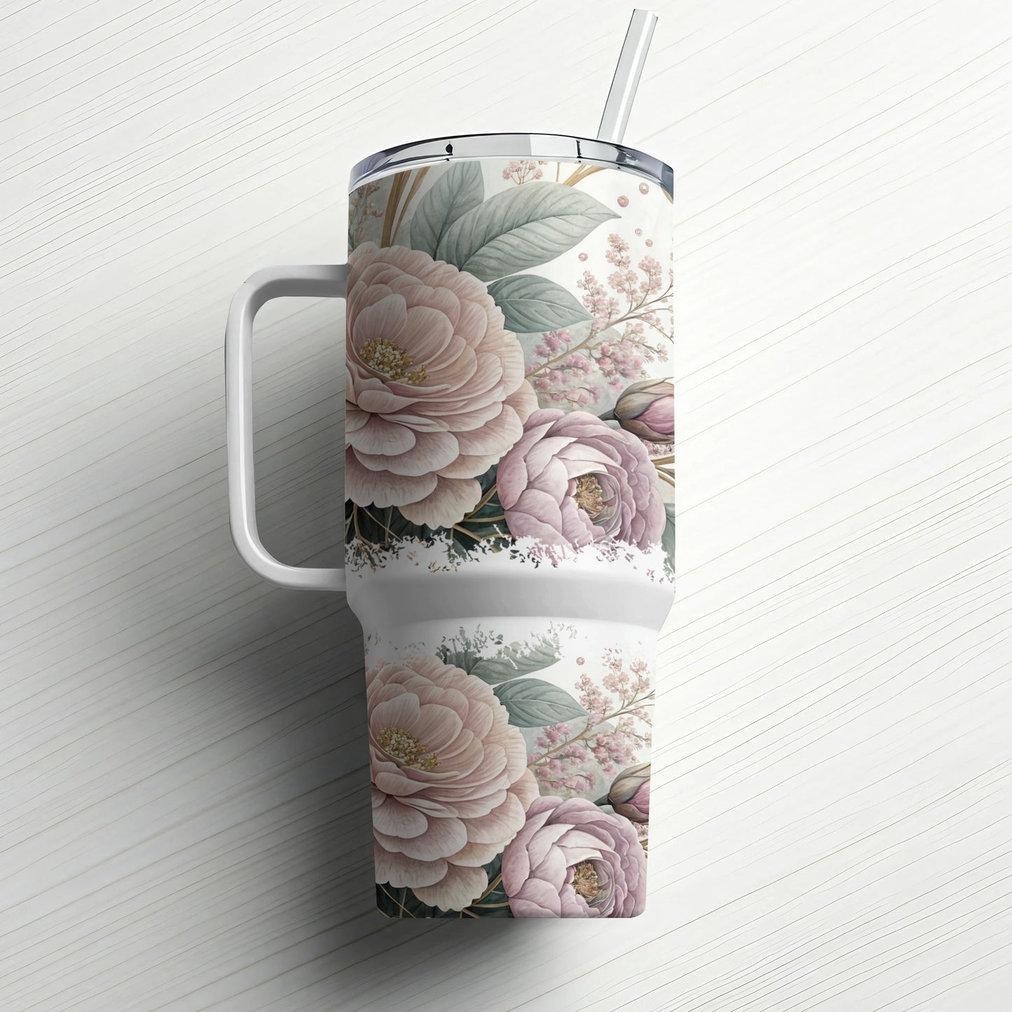 Floral patterned tumbler with handle and straw on white wooden background.