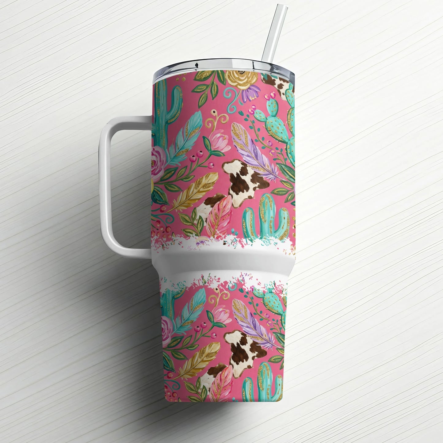Pink tumbler with cow, cactus, and feather pattern and a straw.