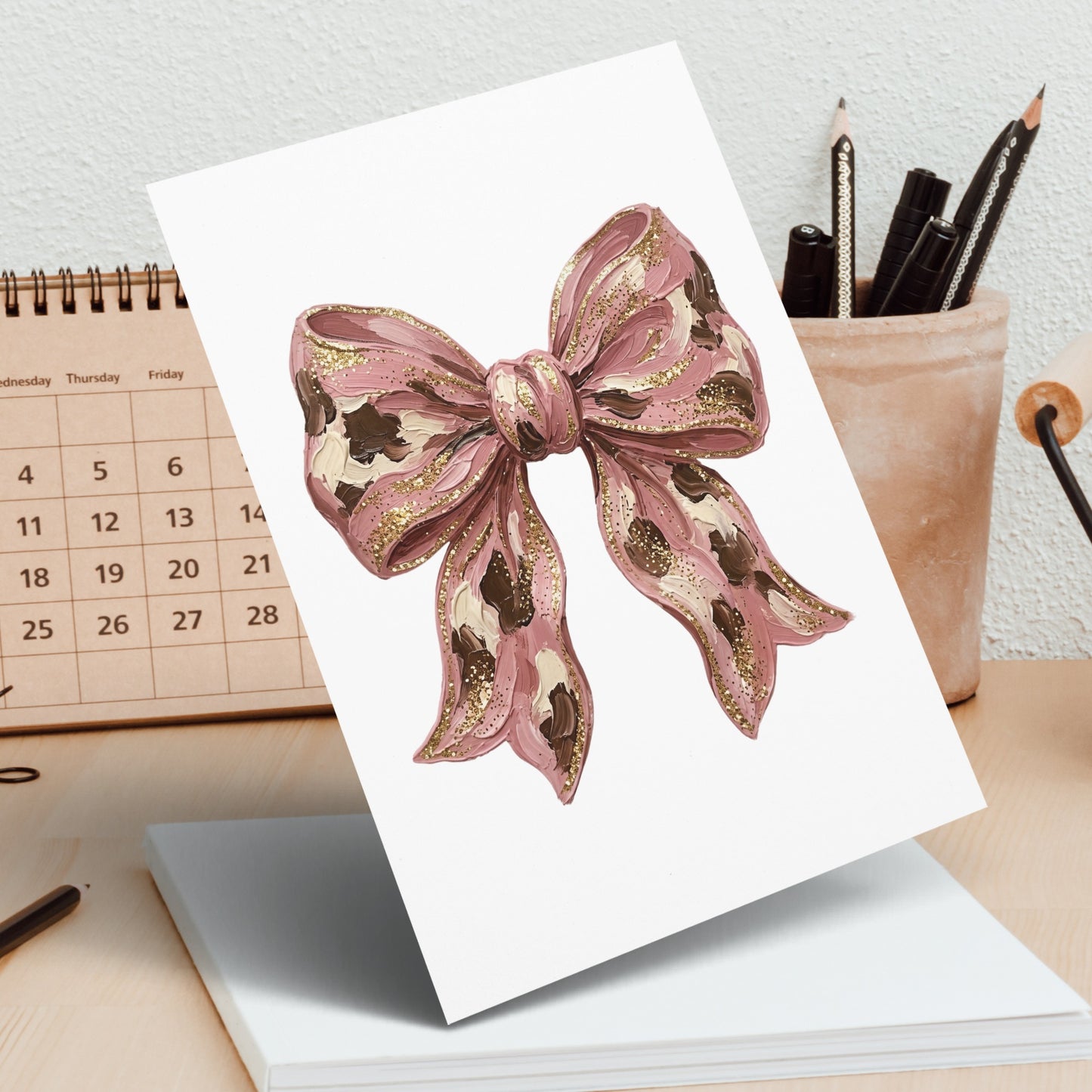 Pink bow with gold glitter accents on a calendar page.