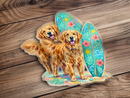 Two golden retrievers stand with surfboards on a sandy beach.
