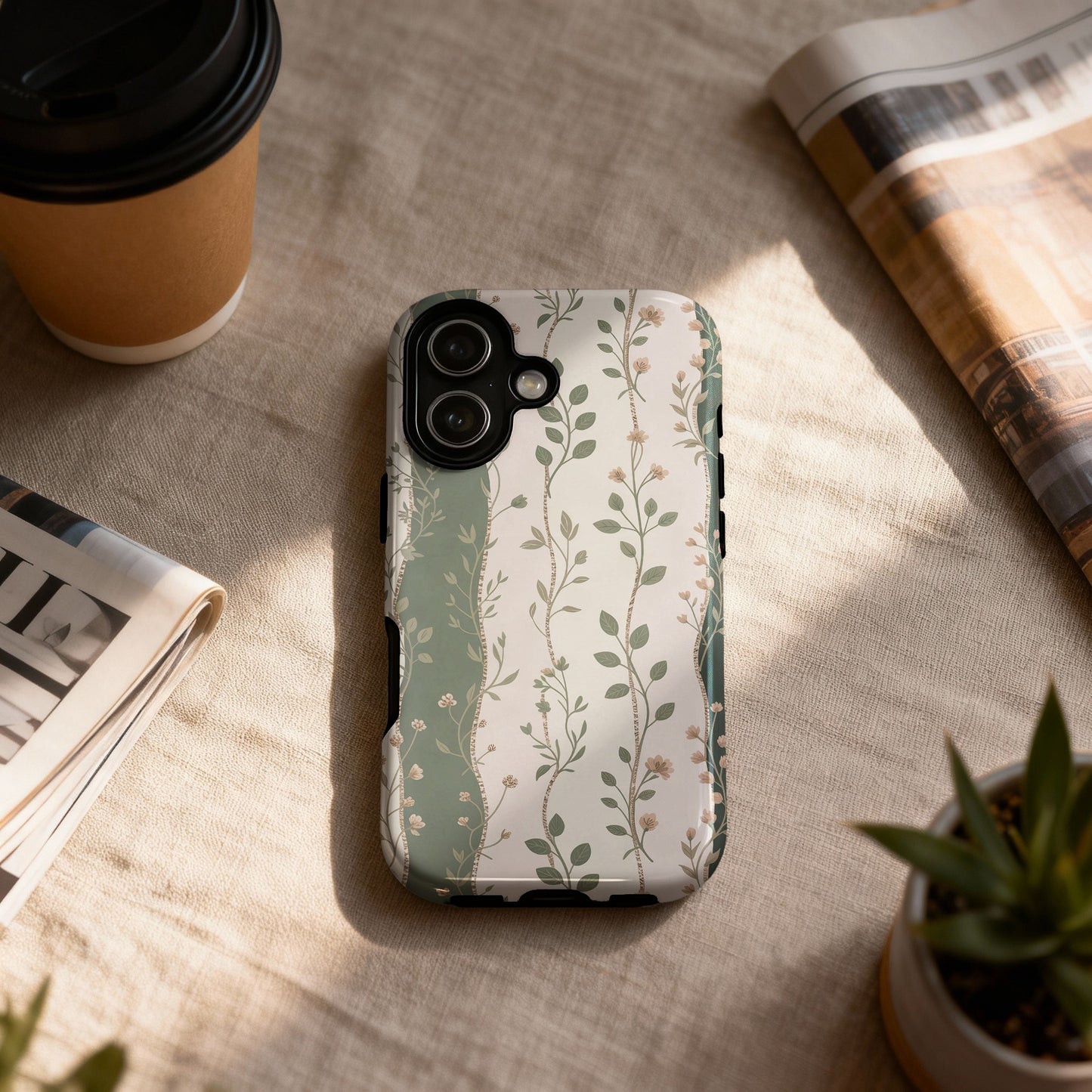 Phone case with a muted floral and vine pattern on a textured surface.