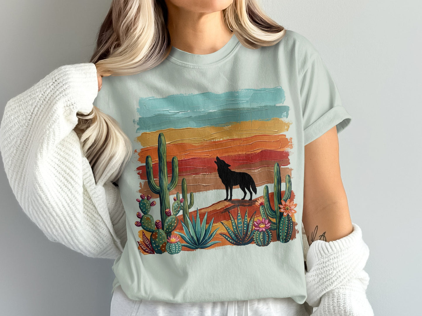 Silhouette of a wolf howling against a colorful desert sunset with cacti.