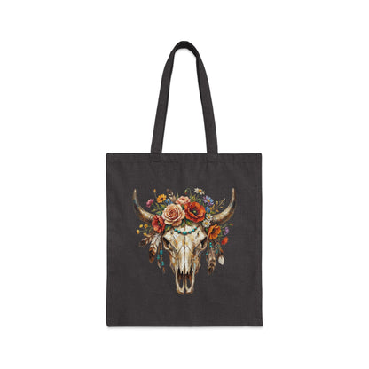 Dark tote bag with a watercolor painting of a bull skull adorned with flowers and feathers.