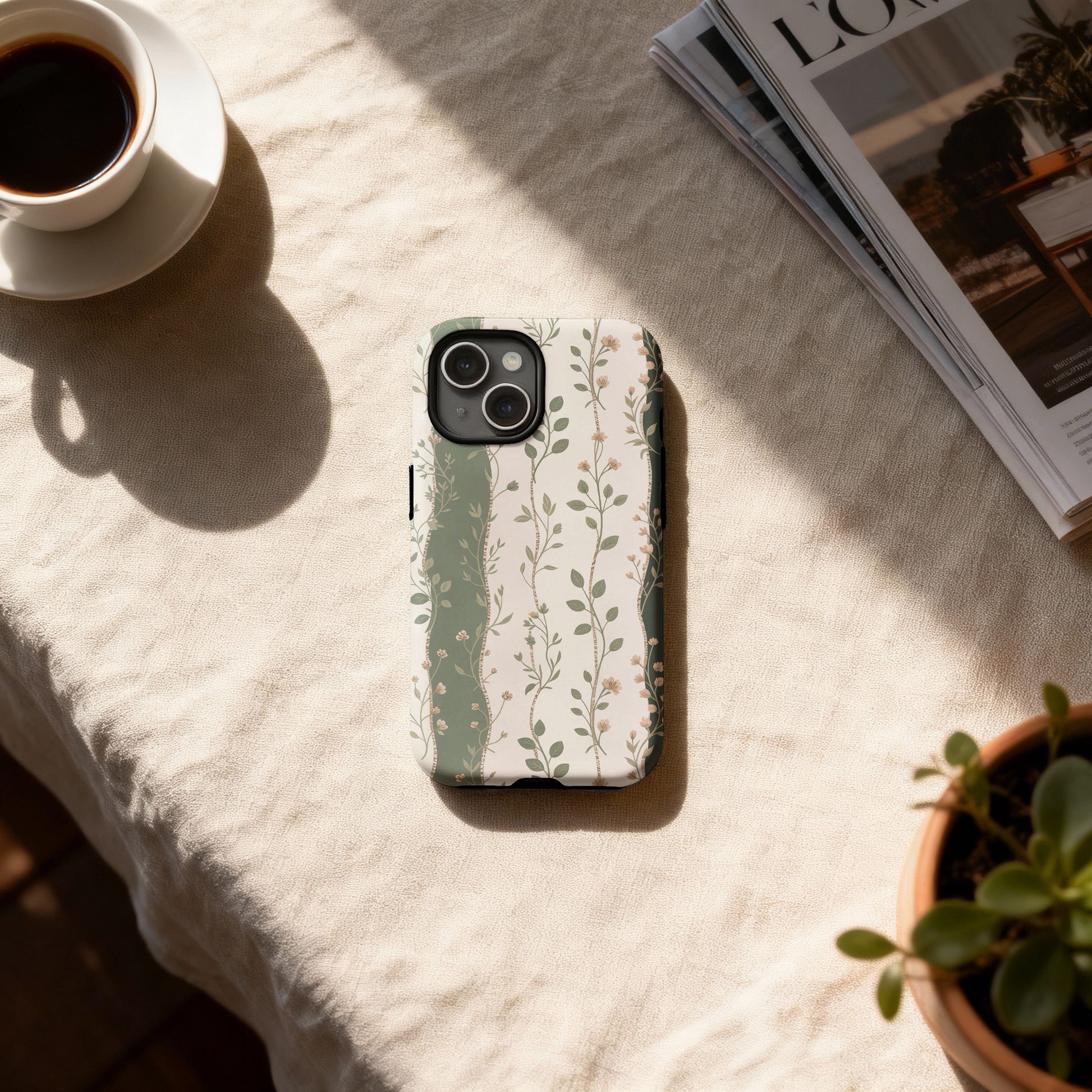 Floral patterned iPhone case with a coffee cup and plant on a table.