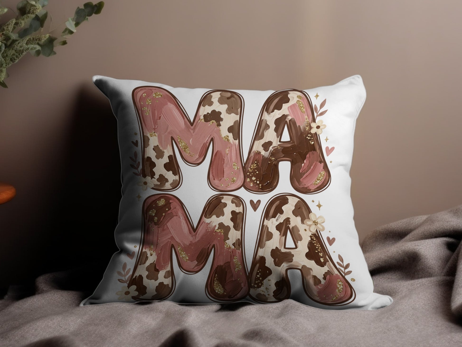 "Mama" text on a decorative pillow with cow print and floral accents.