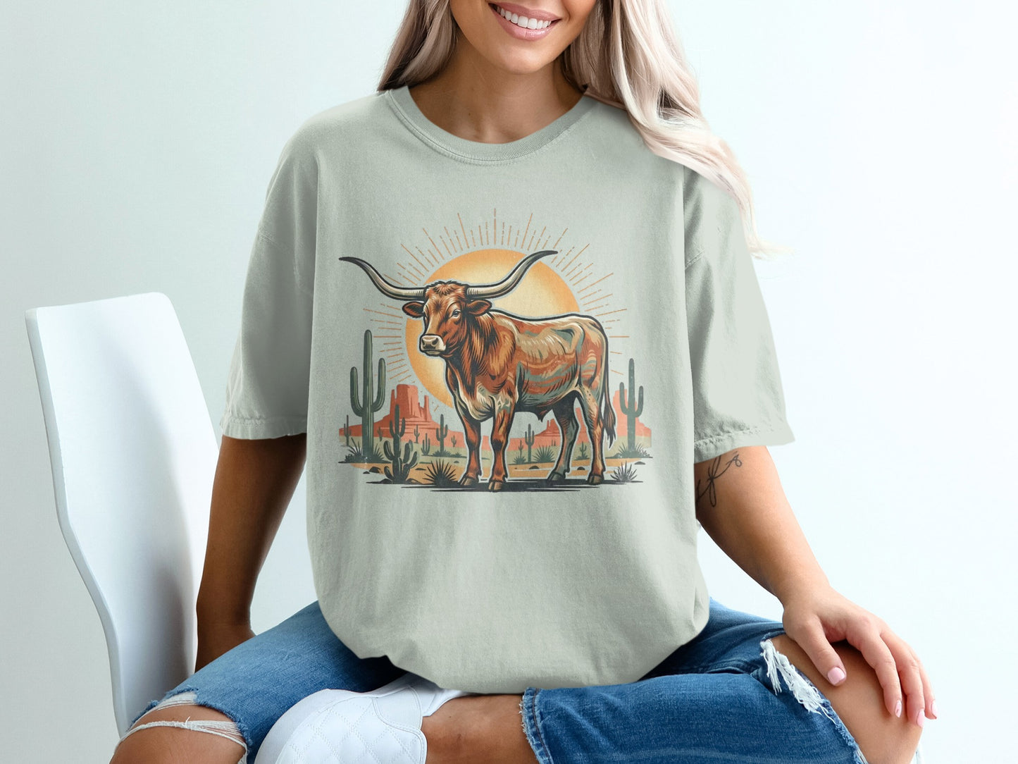 Longhorn steer standing in desert with cacti and sun.
