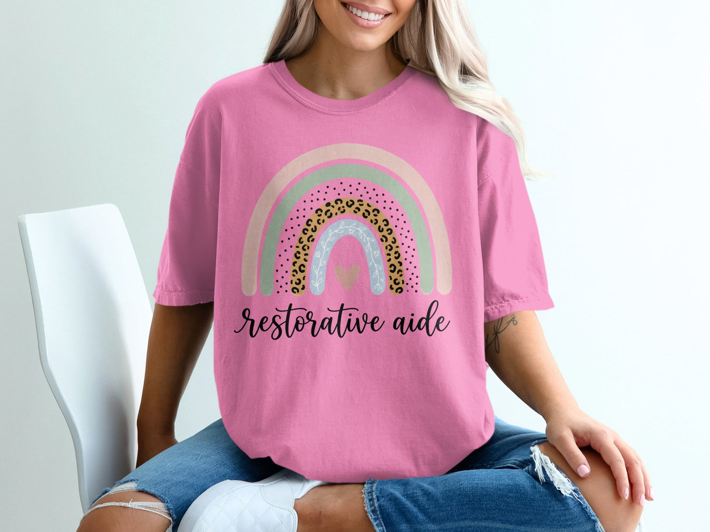 Pink t-shirt with rainbow graphic and text "Restorative aide".