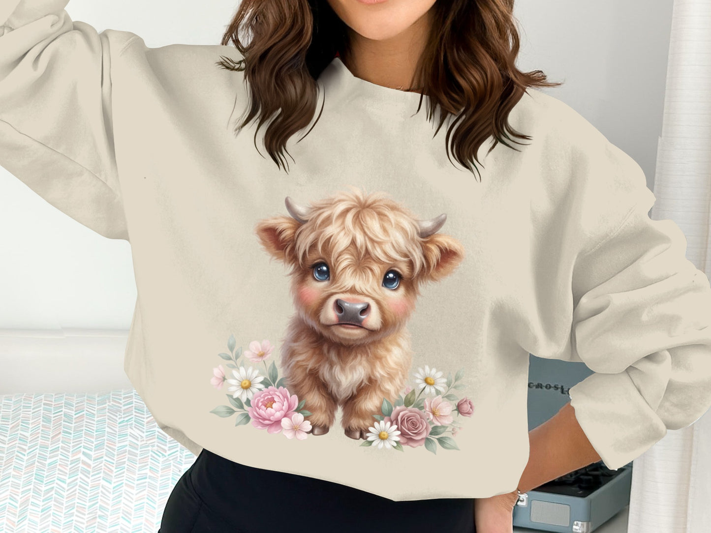 Cream sweatshirt with cute baby highland cow illustration surrounded by flowers.