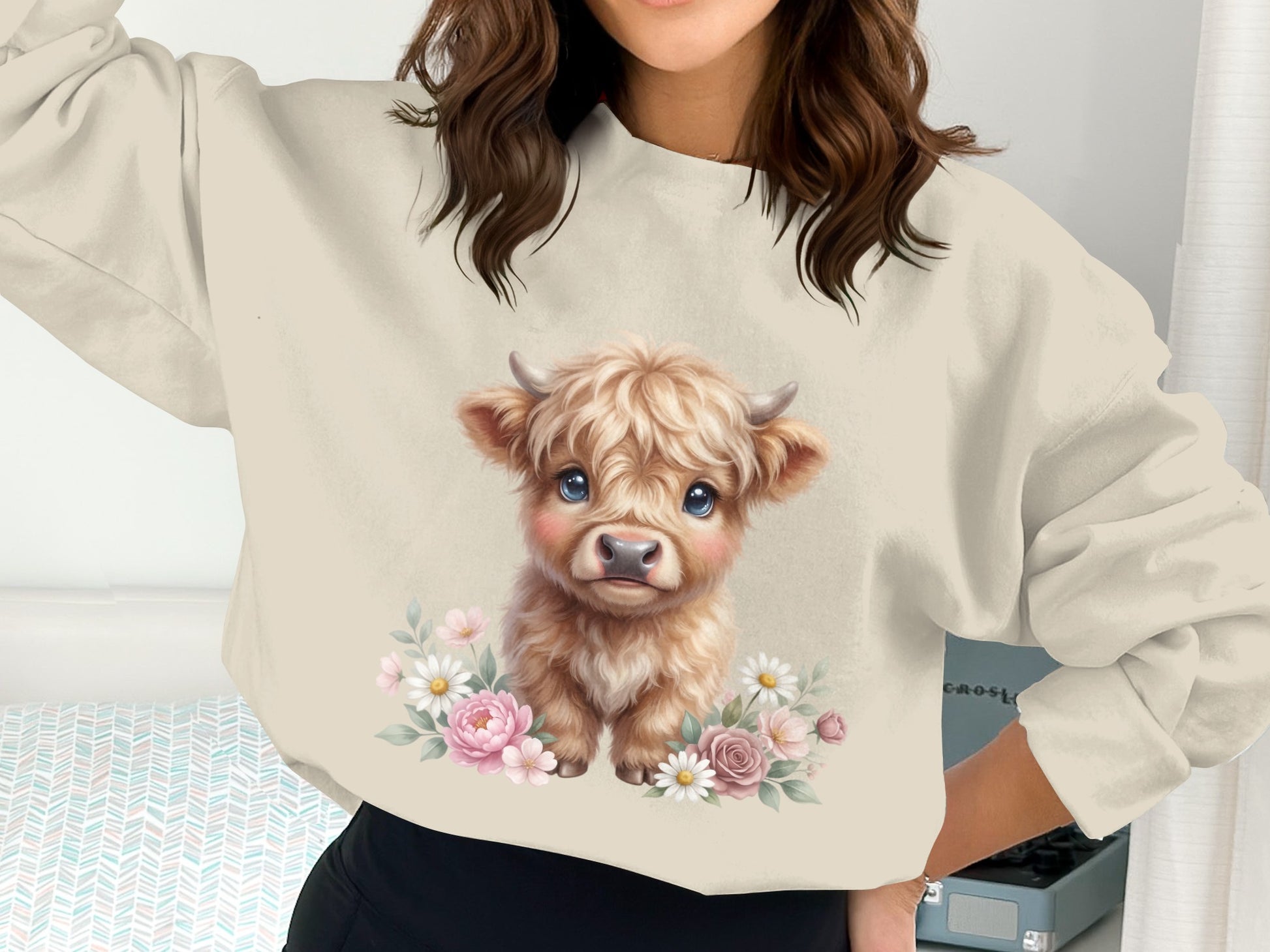 Cream sweatshirt with cute baby highland cow illustration surrounded by flowers.
