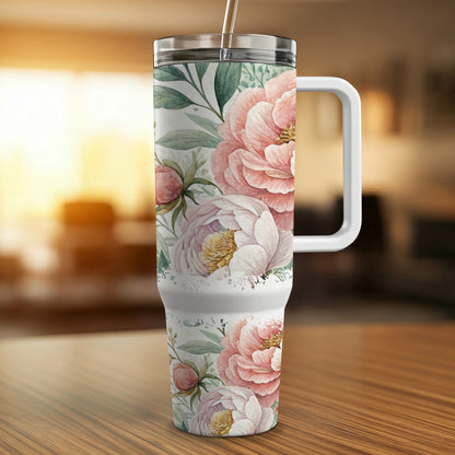 White tumbler with pink peonies and green leaves, on a wooden table.