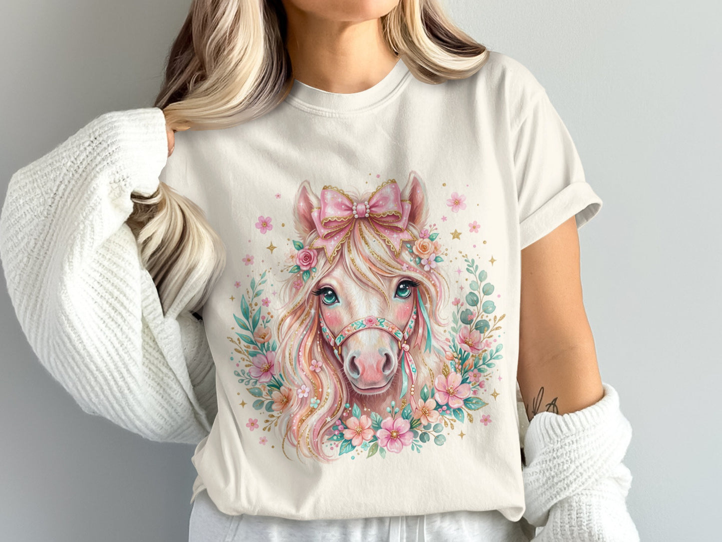 Cream t-shirt with a watercolor horse graphic adorned with flowers and a bow.