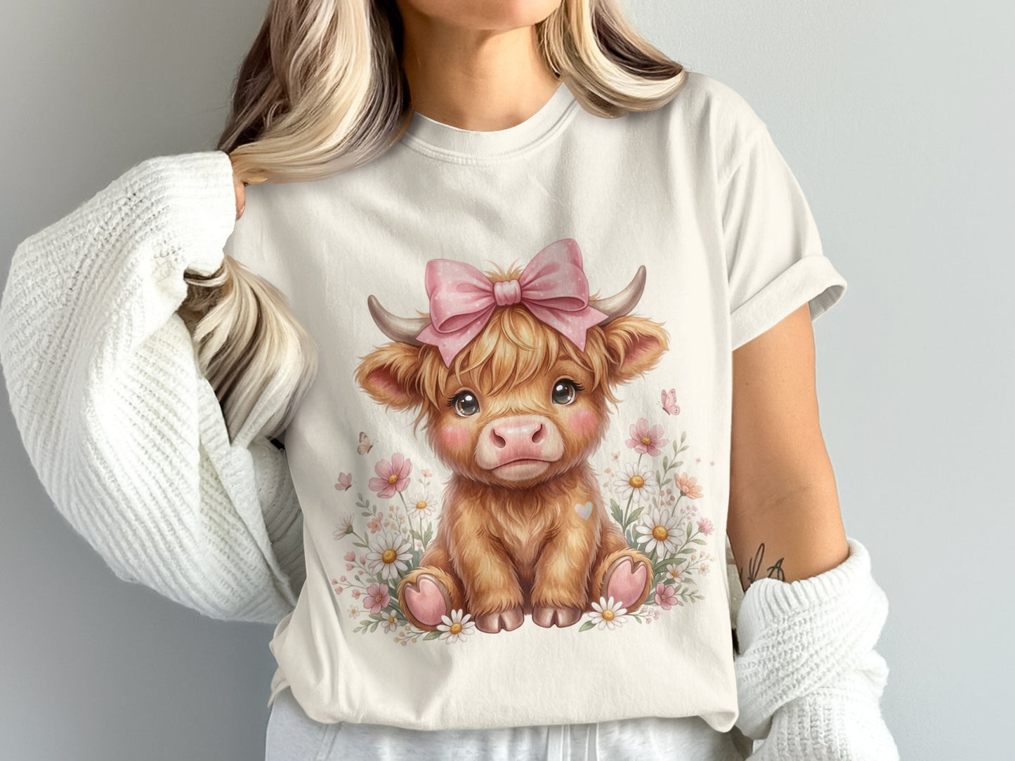 White t-shirt with a cute brown highland cow illustration wearing a pink bow.