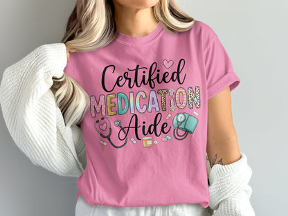 Pink t-shirt with "Certified Medication Aide" text and medical icons.