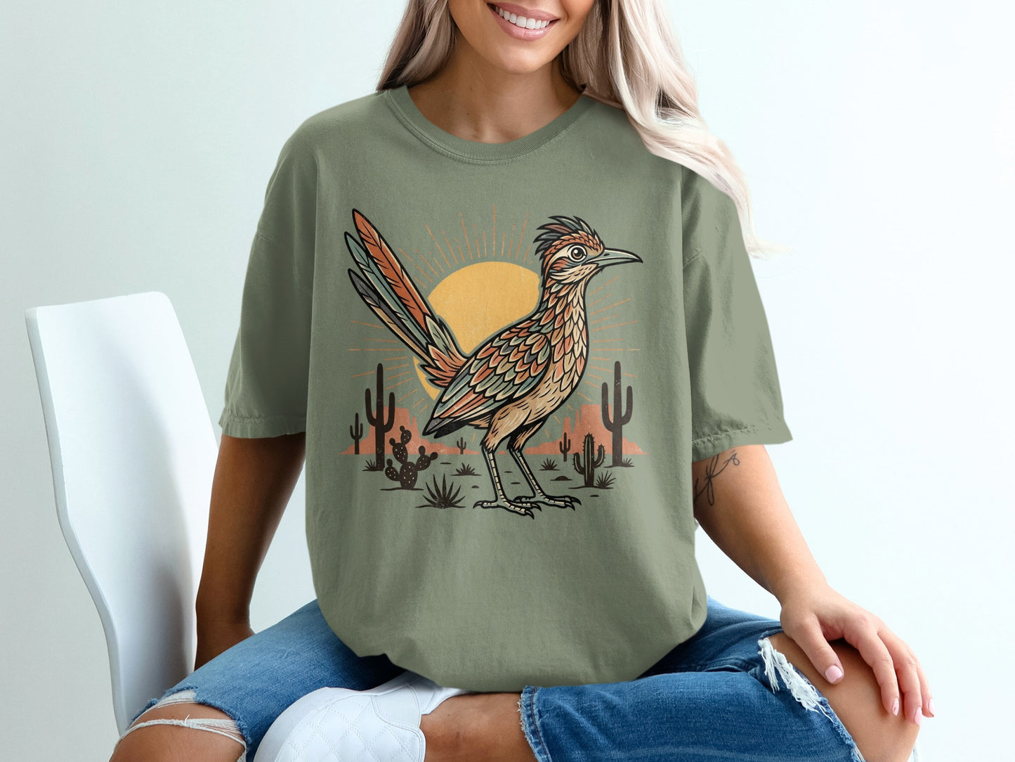 T-shirt with roadrunner, sun, and cacti desert scene graphic.
