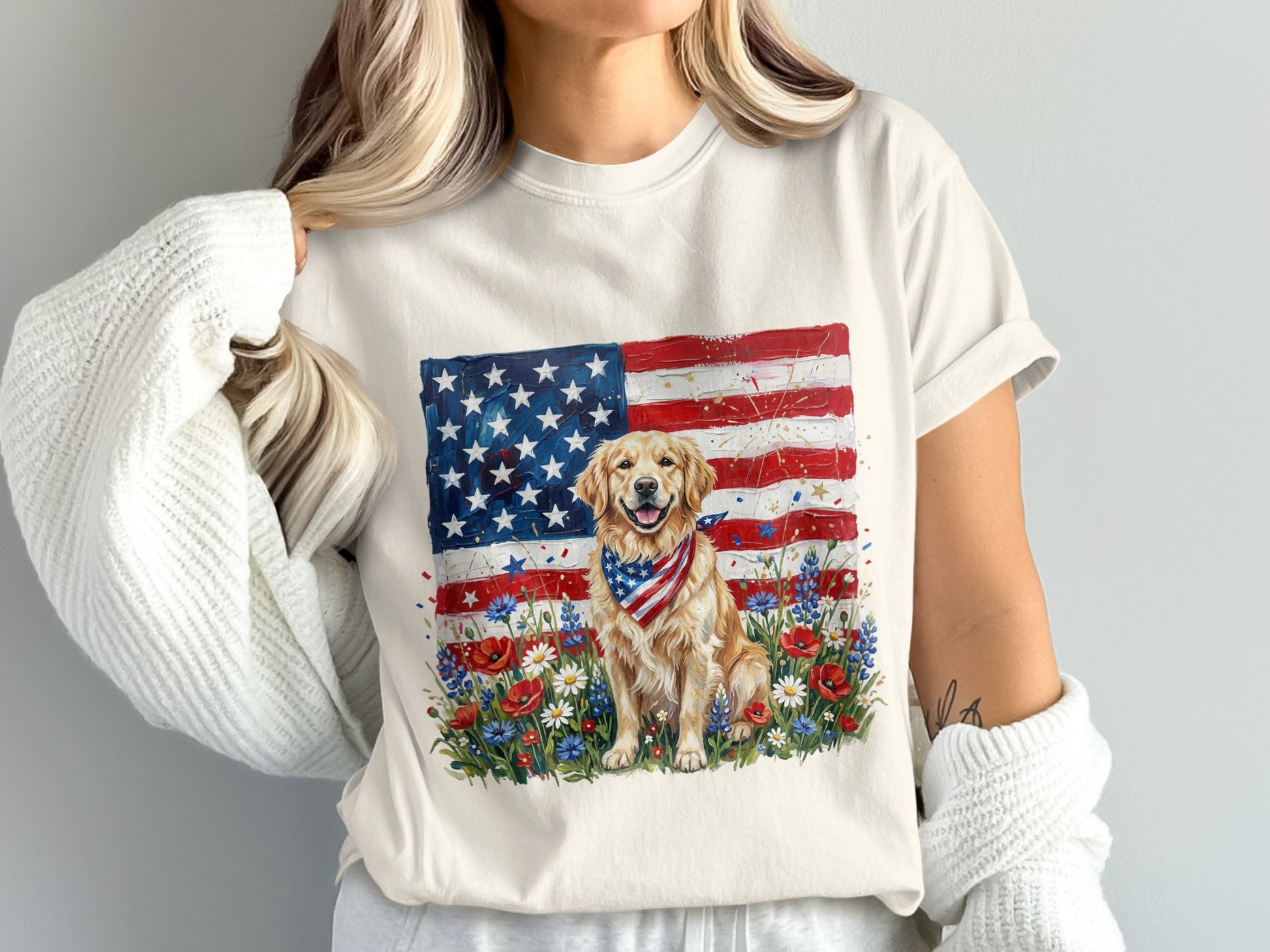 Golden retriever wearing bandana sits in front of American flag and wildflowers.