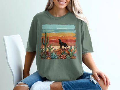Green t-shirt with desert scene, coyote howling at sunset, cacti and flowers.