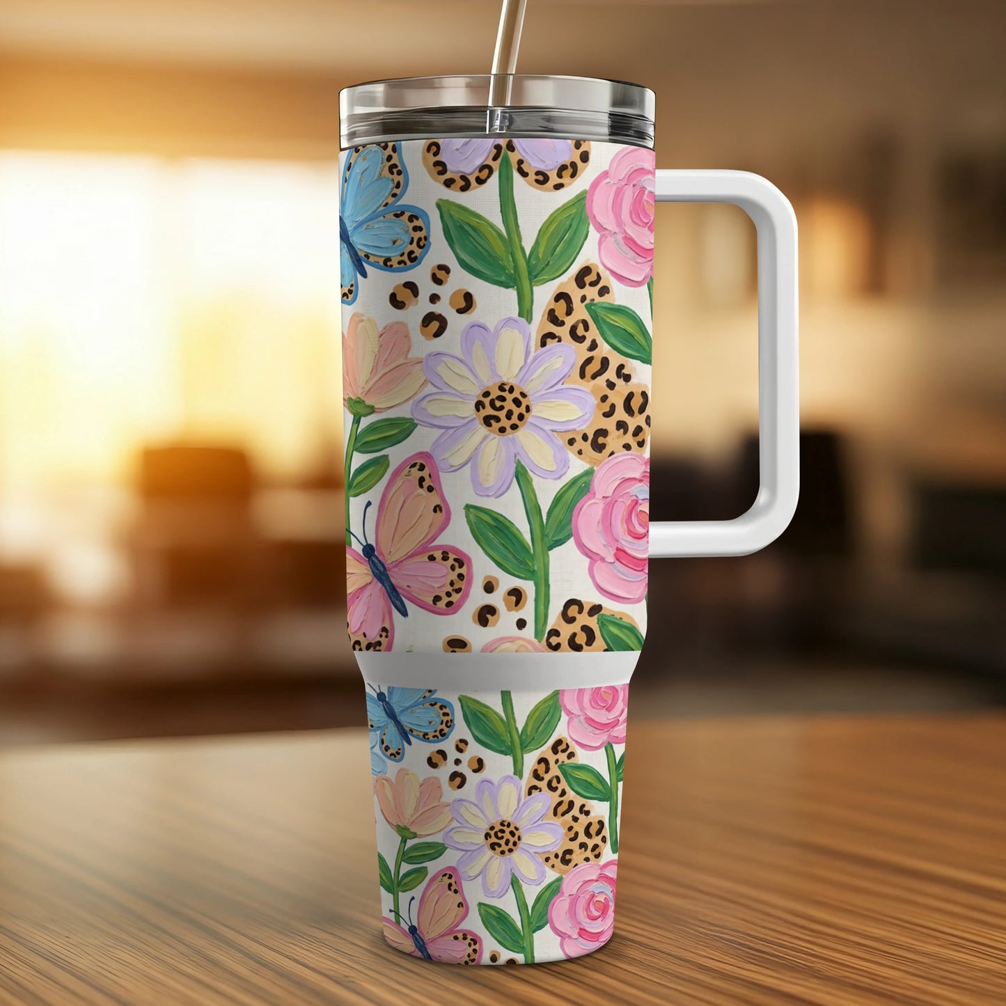 Floral and butterfly patterned tumbler with handle and straw.