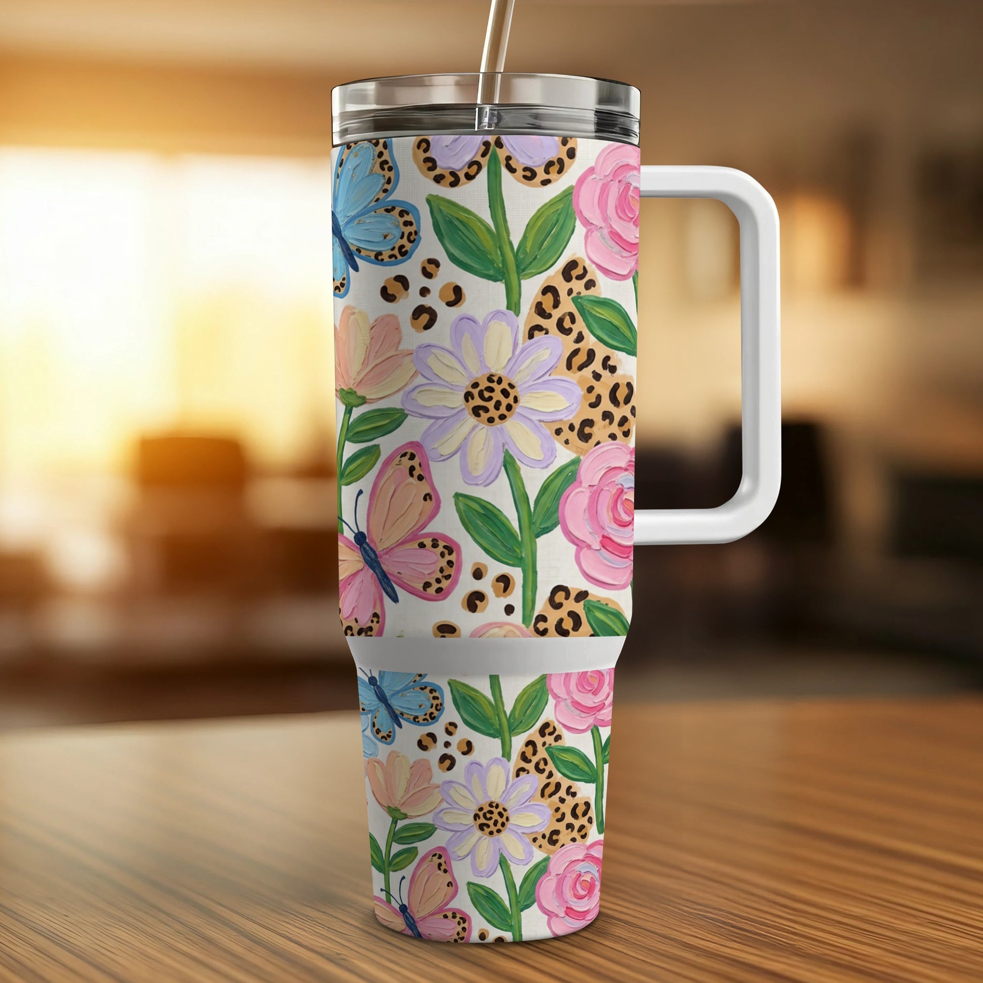 Floral and butterfly patterned tumbler with handle and straw.