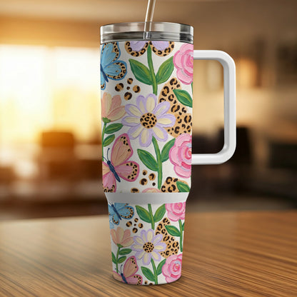 Floral and butterfly patterned tumbler with handle and straw.