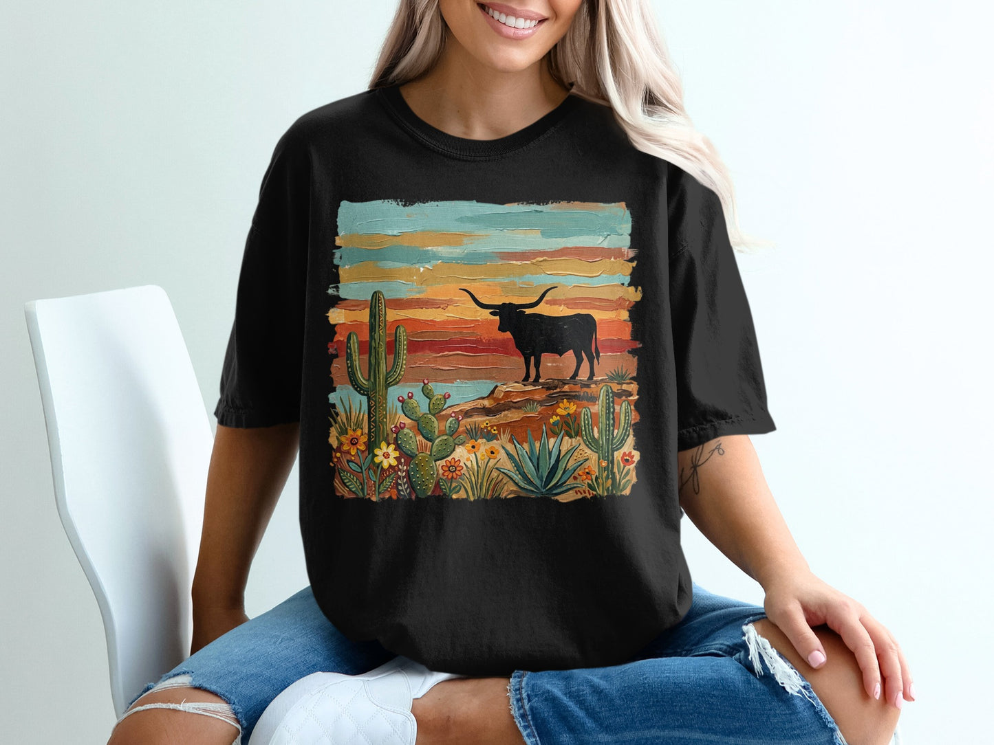 Black t-shirt with desert landscape featuring a longhorn steer, cacti, and colorful sunset.