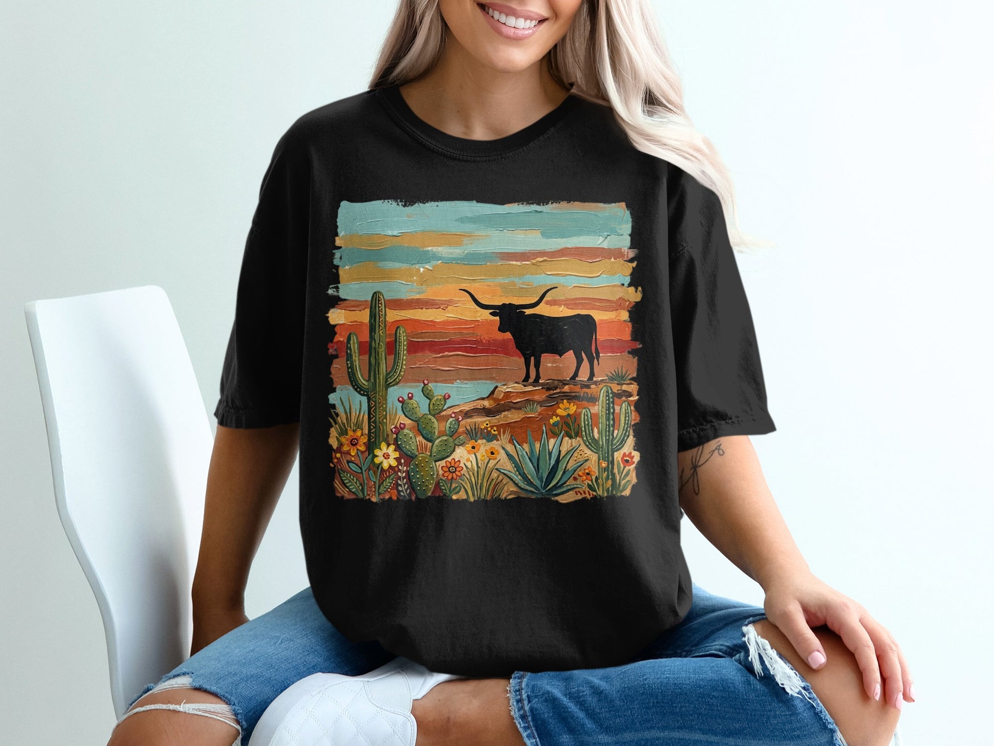 Black t-shirt with desert landscape featuring a longhorn steer, cacti, and colorful sunset.