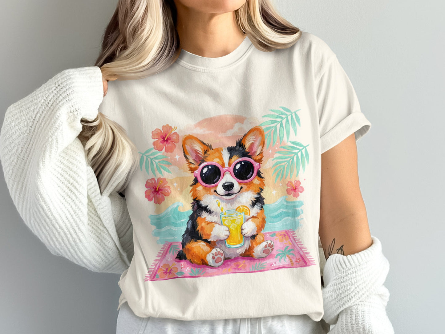 Corgi wearing sunglasses drinks from a cup on a beach mat.