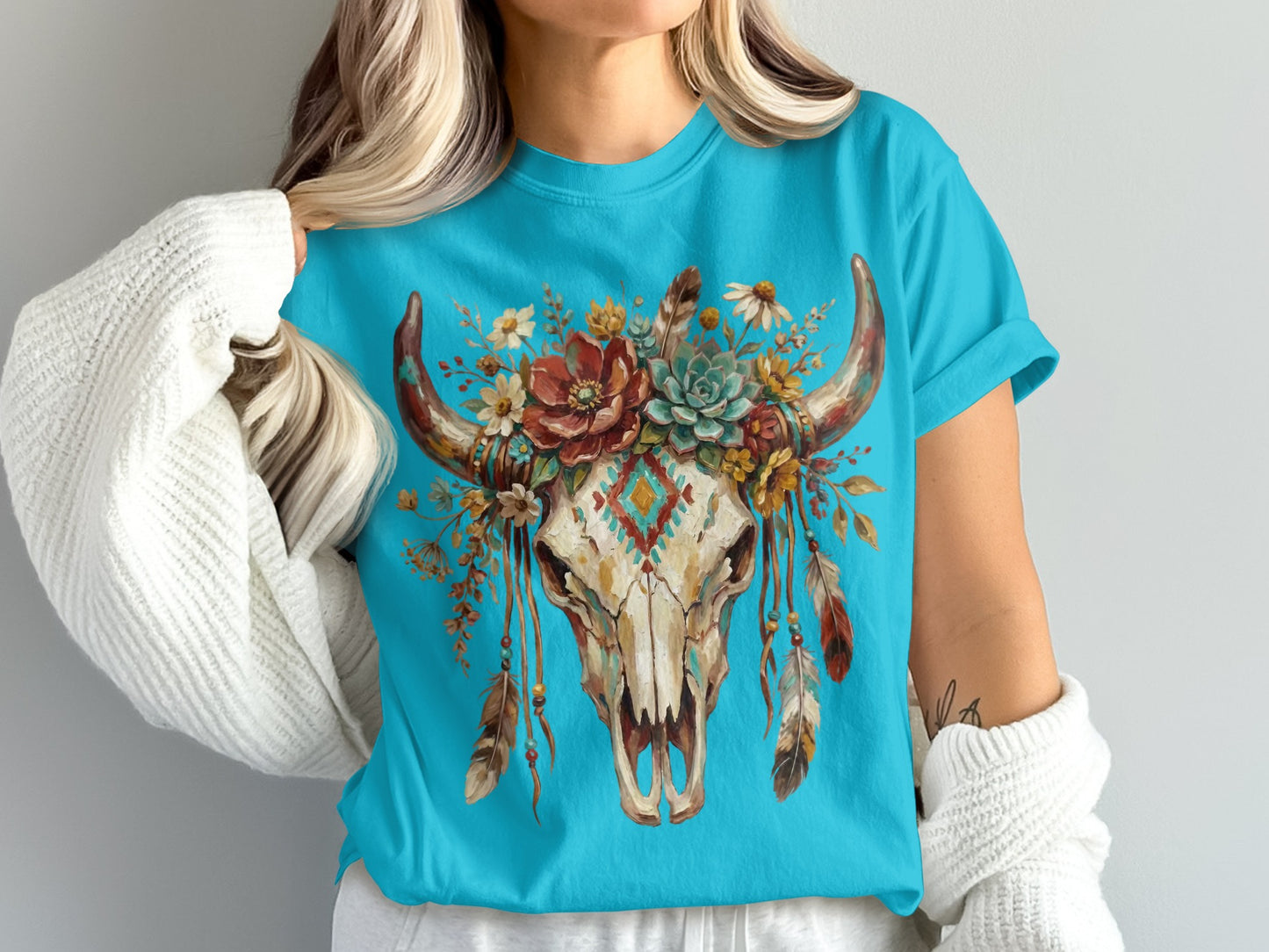 Turquoise t-shirt with a skull featuring flowers, feathers, and a geometric pattern.