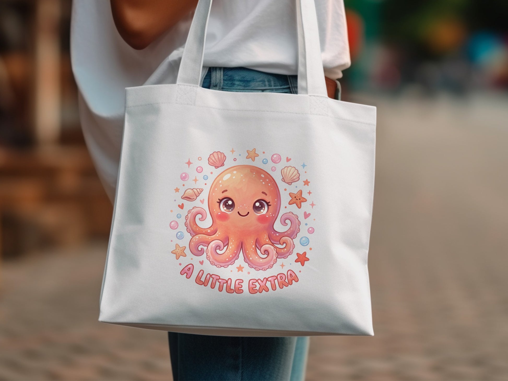White tote bag with a cartoon octopus and "A LITTLE EXTRA" text.