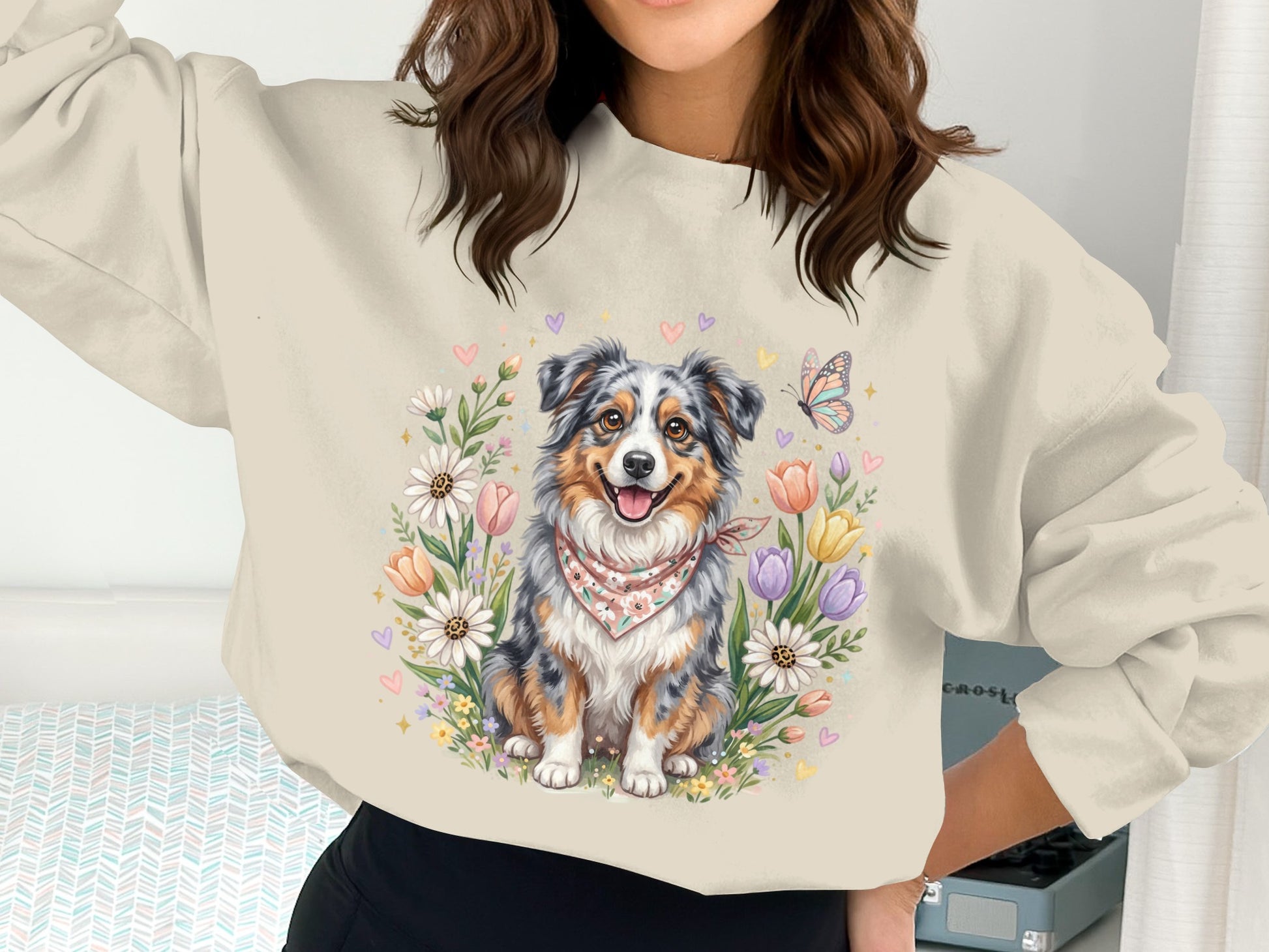 Woman wearing a cream sweatshirt with a graphic of a dog surrounded by flowers and hearts.