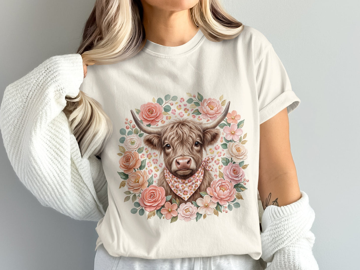 Cream t-shirt with a Highland cow graphic surrounded by floral wreath.