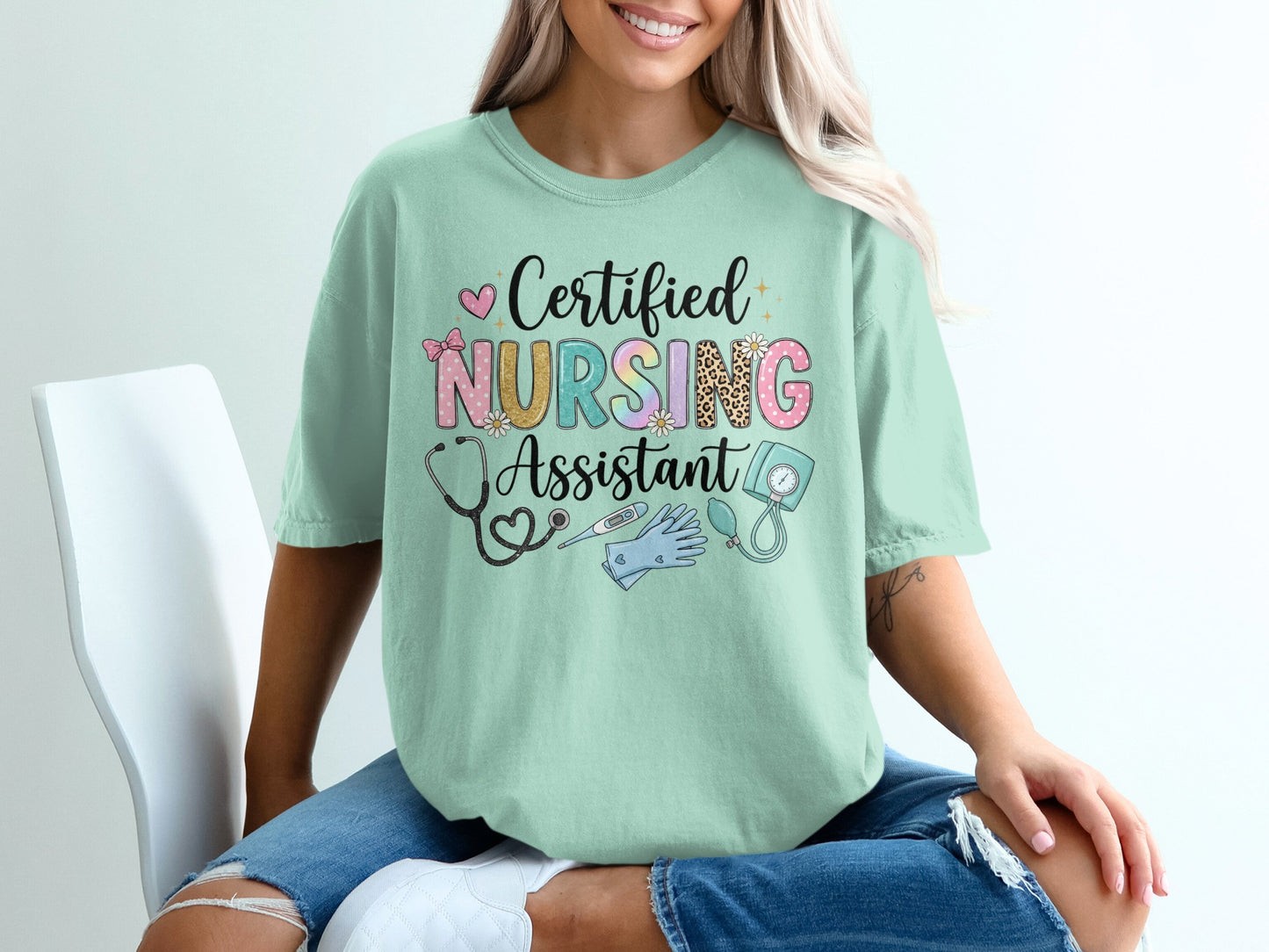 Mint green t-shirt with "Certified Nursing Assistant" in colorful lettering and medical icons.