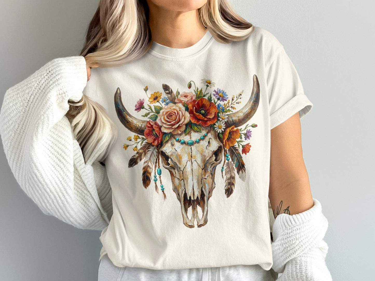 Cream t-shirt with a floral adorned bull skull graphic and turquoise beads.