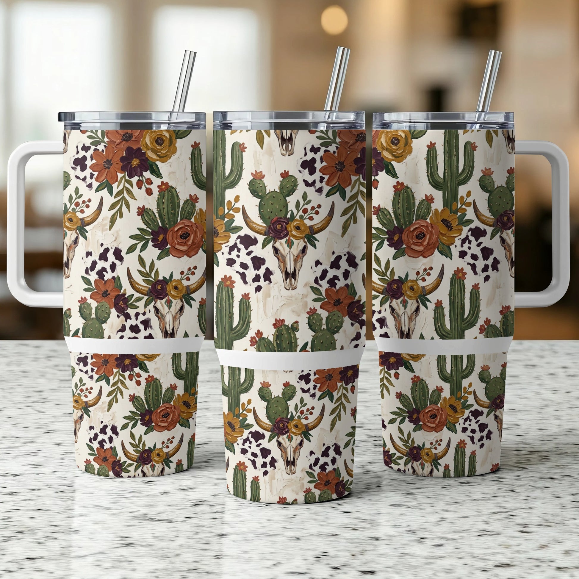 Three tumblers with a desert floral and cattle skull pattern, featuring straws and handles.