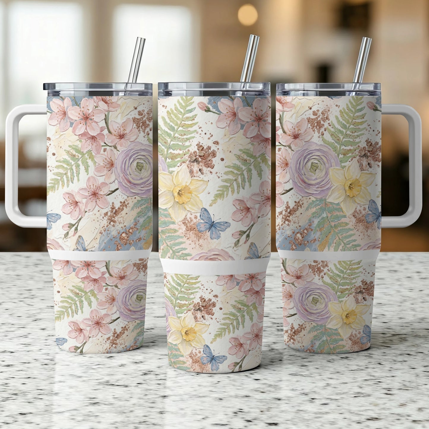 Three floral tumblers with butterfly and fern designs and metal straws.