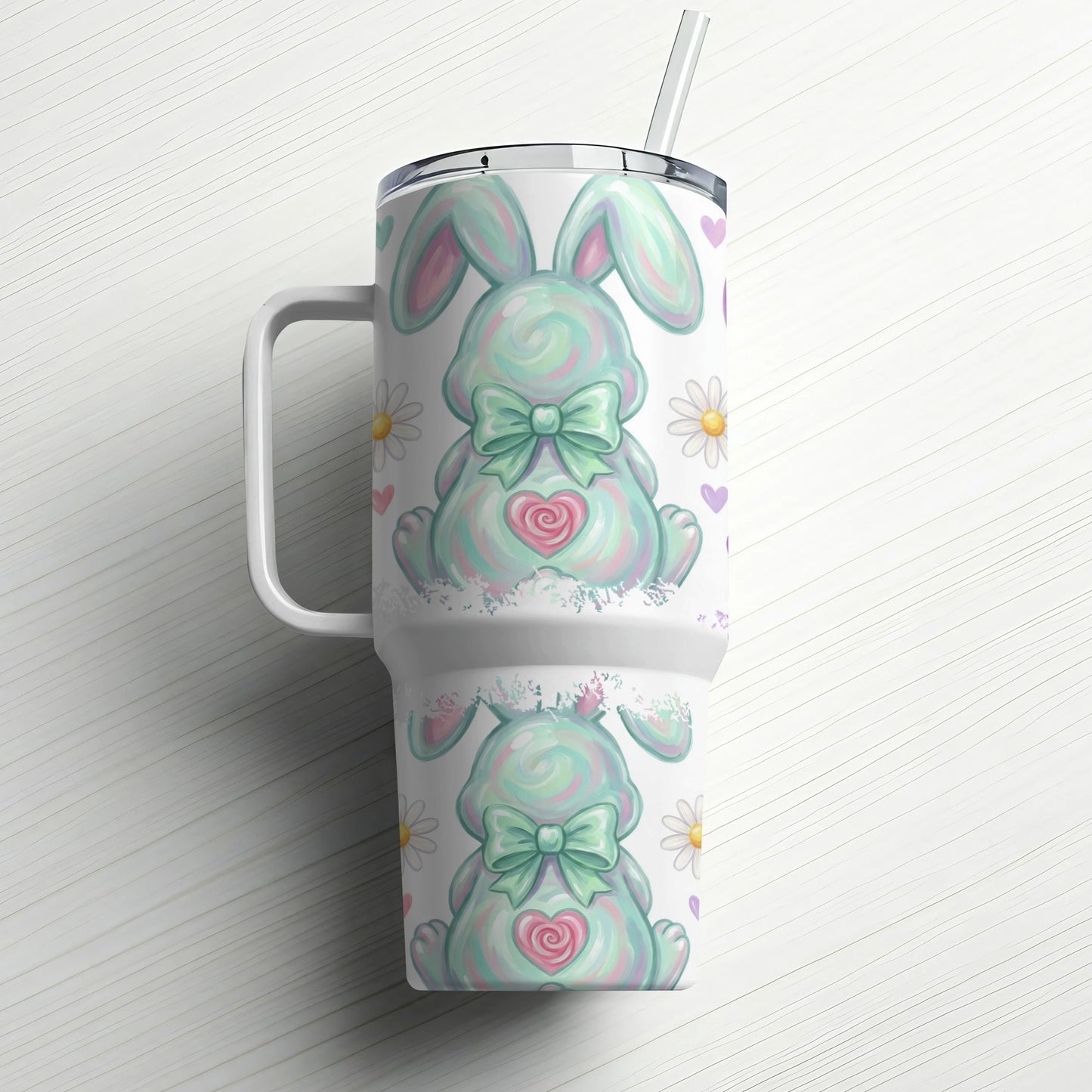 Mint green bunny tumbler with bow, daisies, and hearts on white wood background.
