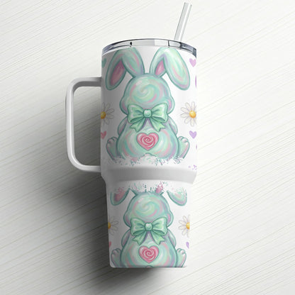 Mint green bunny tumbler with bow, daisies, and hearts on white wood background.