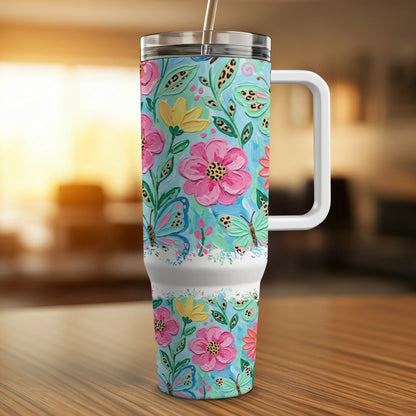 Blue tumbler with floral and butterfly pattern, handle, and straw.