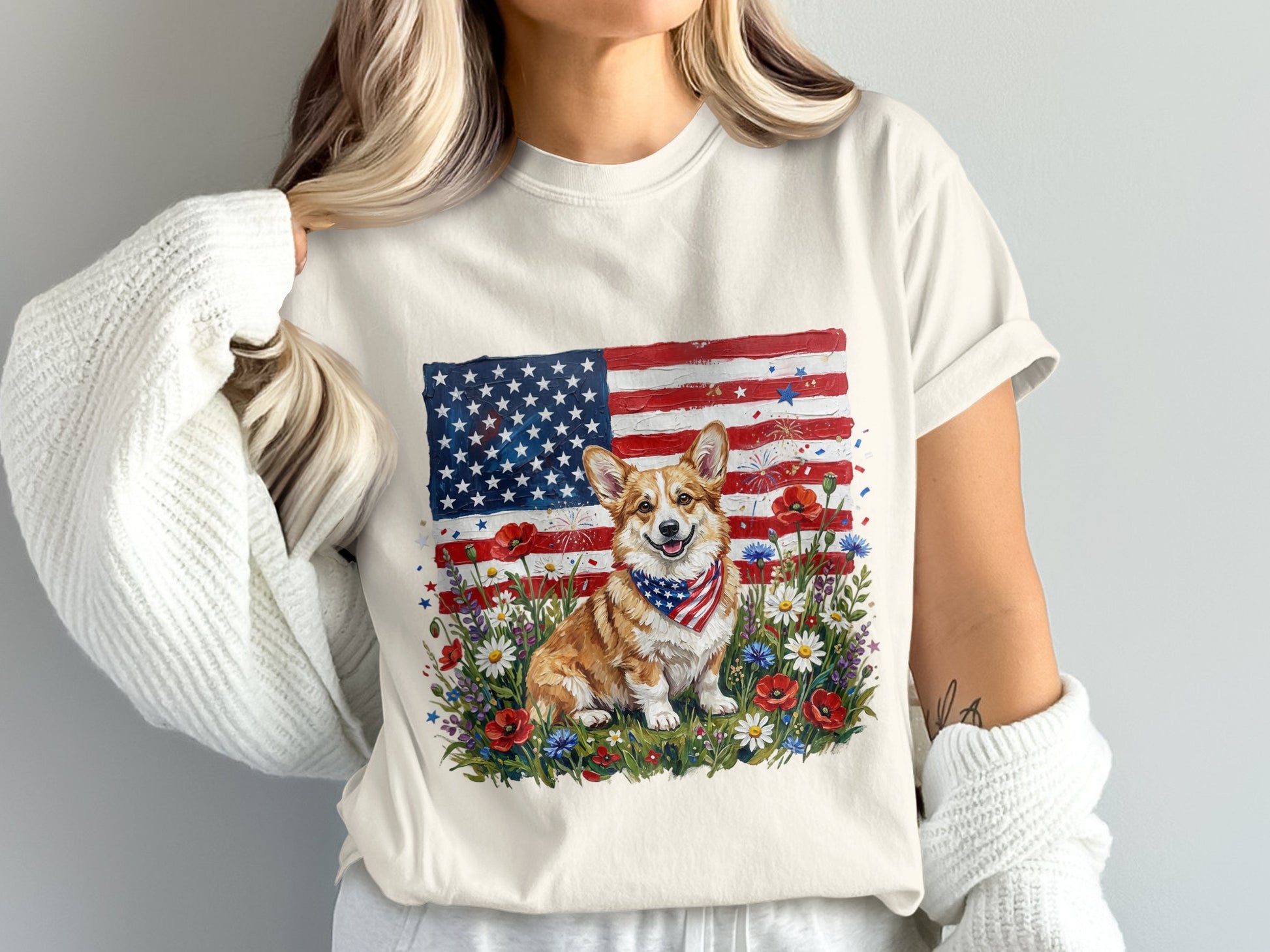 Corgi wearing a bandana sits in front of an American flag and wildflowers.