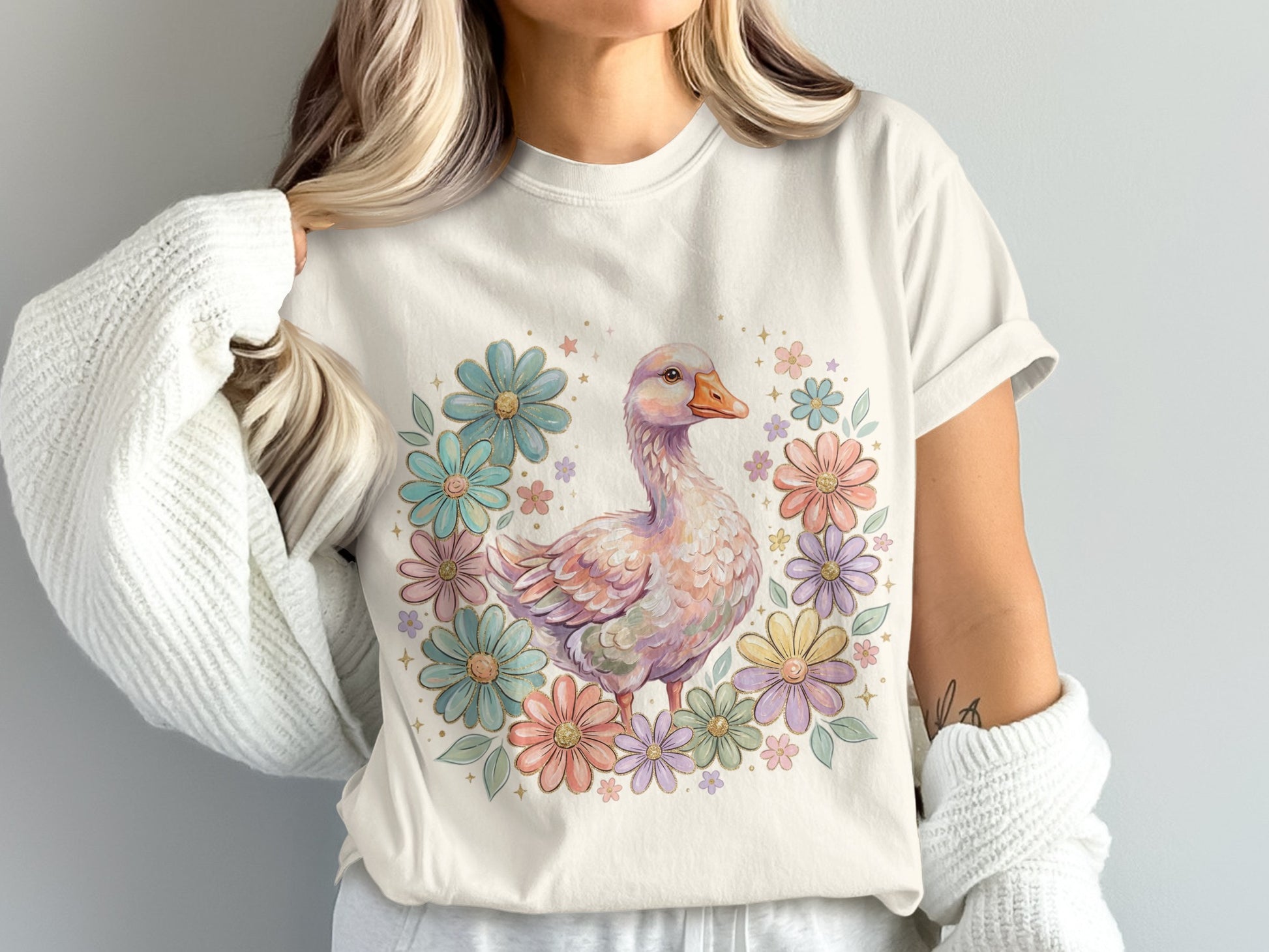 Cream t-shirt with a pastel duck surrounded by colorful flowers.