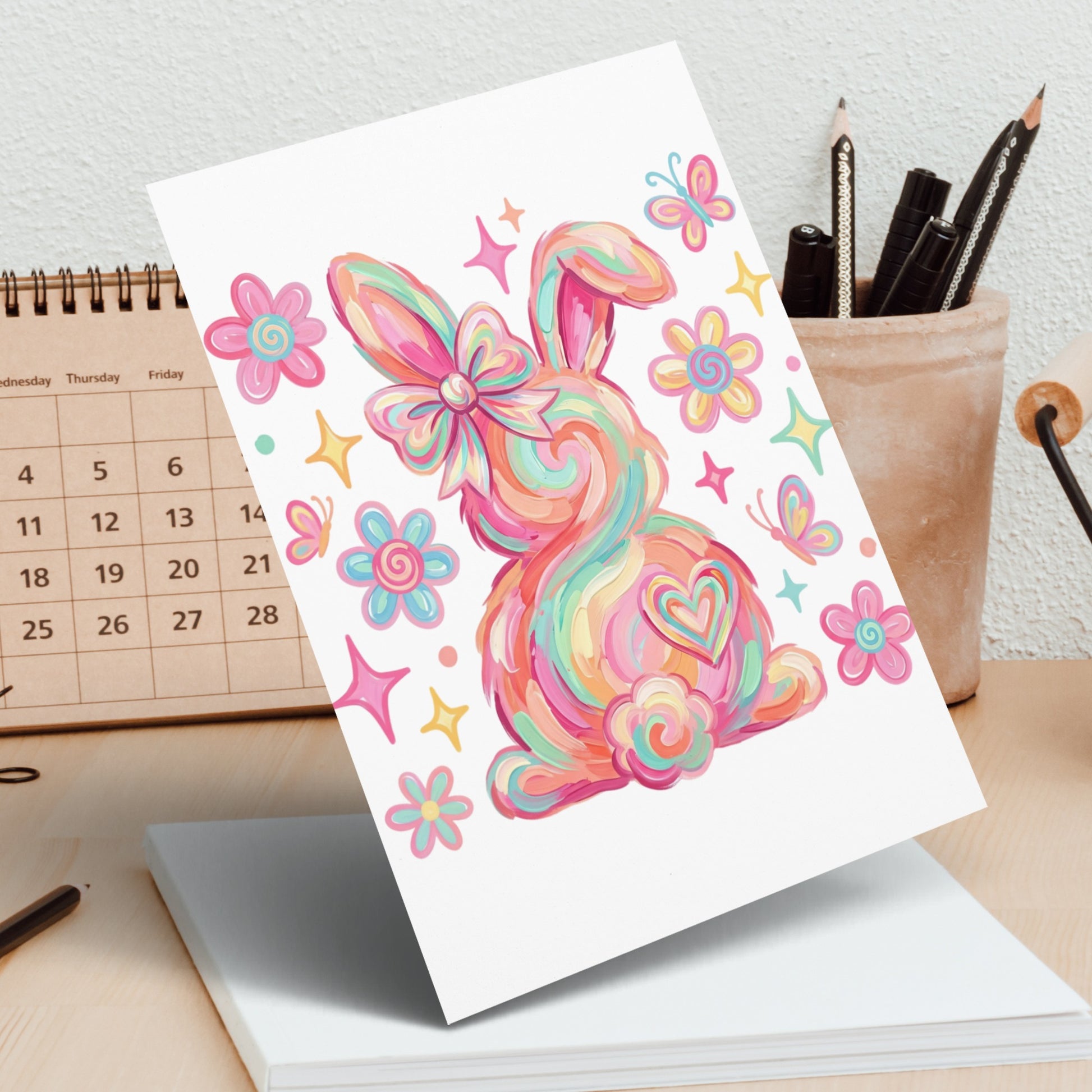 Colorful abstract bunny with a bow and butterflies on a card.