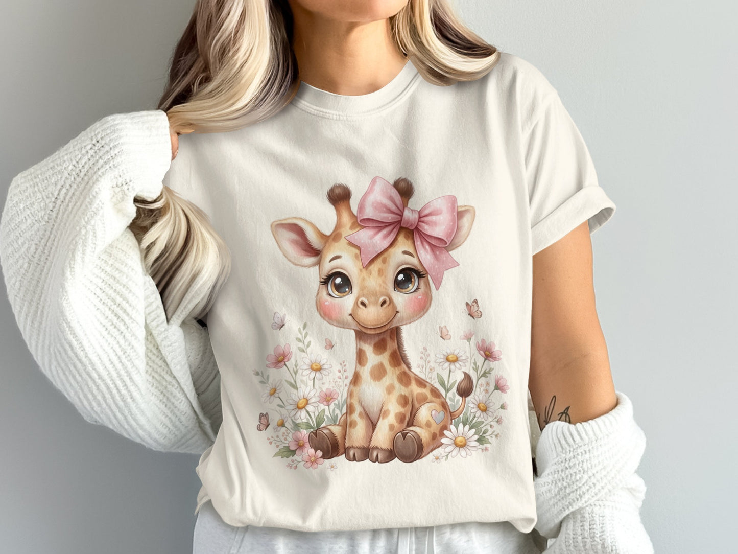 Cream t-shirt with a cartoon baby giraffe and pink bow among flowers.