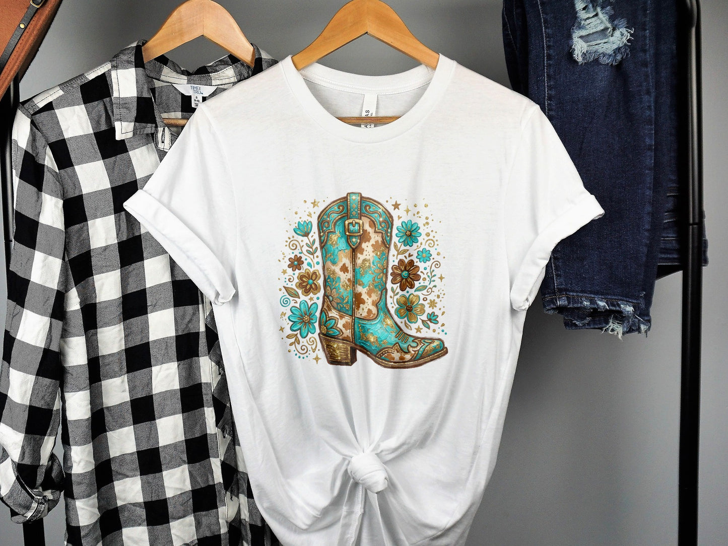 White t-shirt with a turquoise and brown cowboy boot floral graphic.
