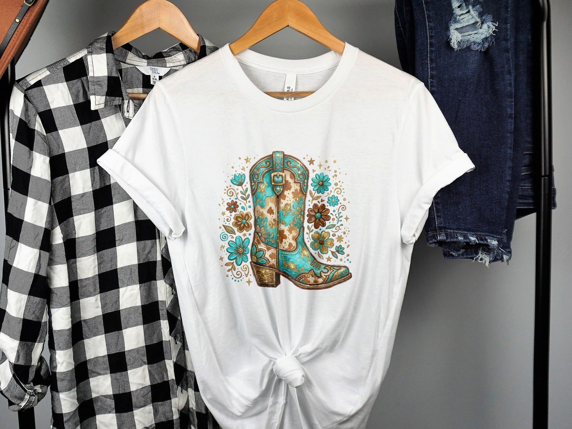 White t-shirt with a turquoise and brown cowboy boot floral graphic.