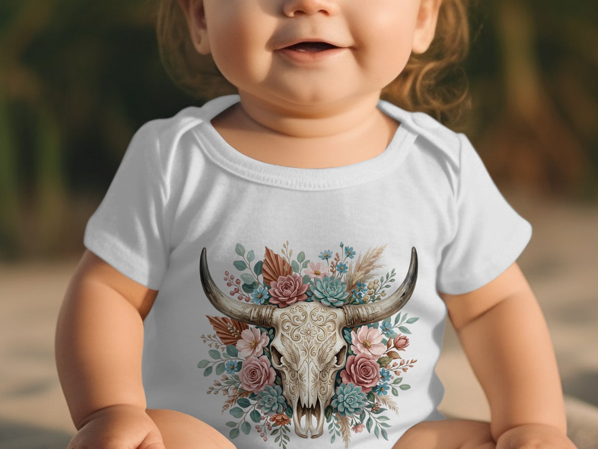 Baby in white bodysuit with floral bull skull graphic.