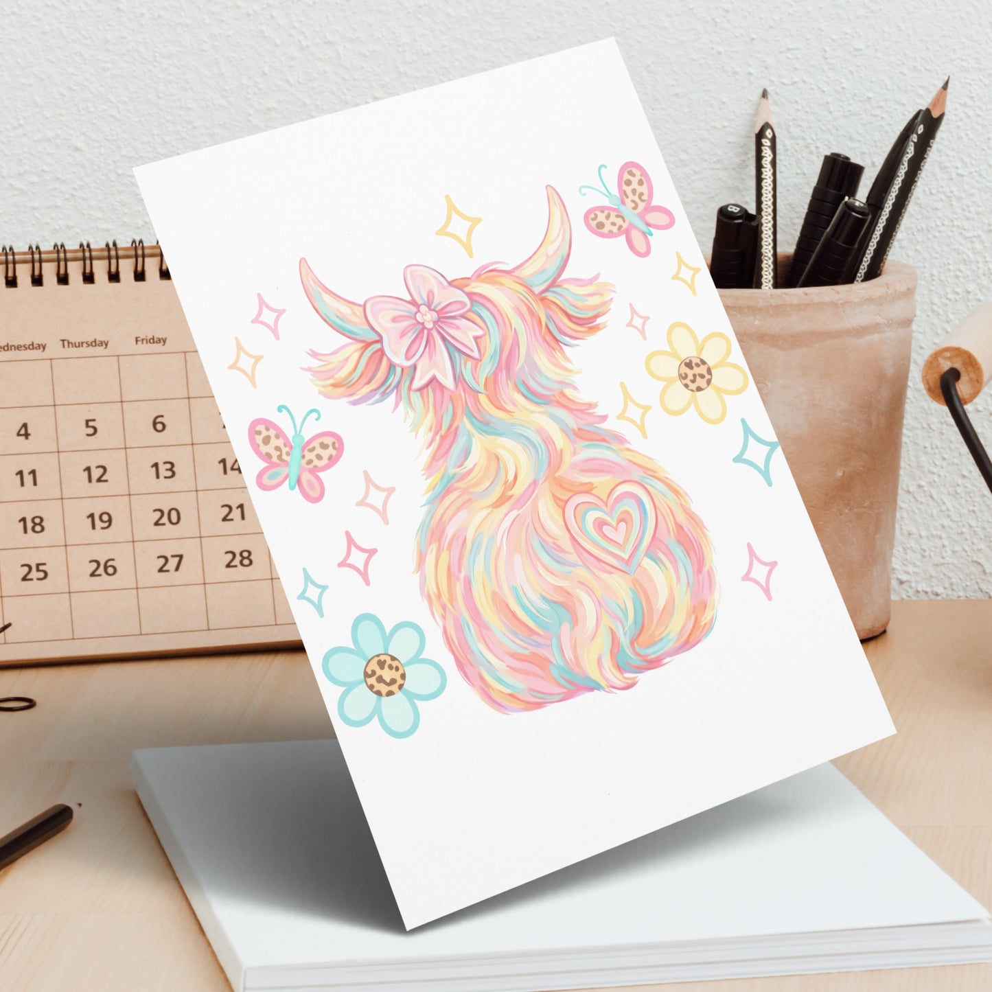 Colorful Highland cow with butterflies and flowers on a greeting card.