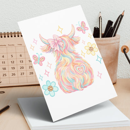 Colorful Highland cow with butterflies and flowers on a greeting card.