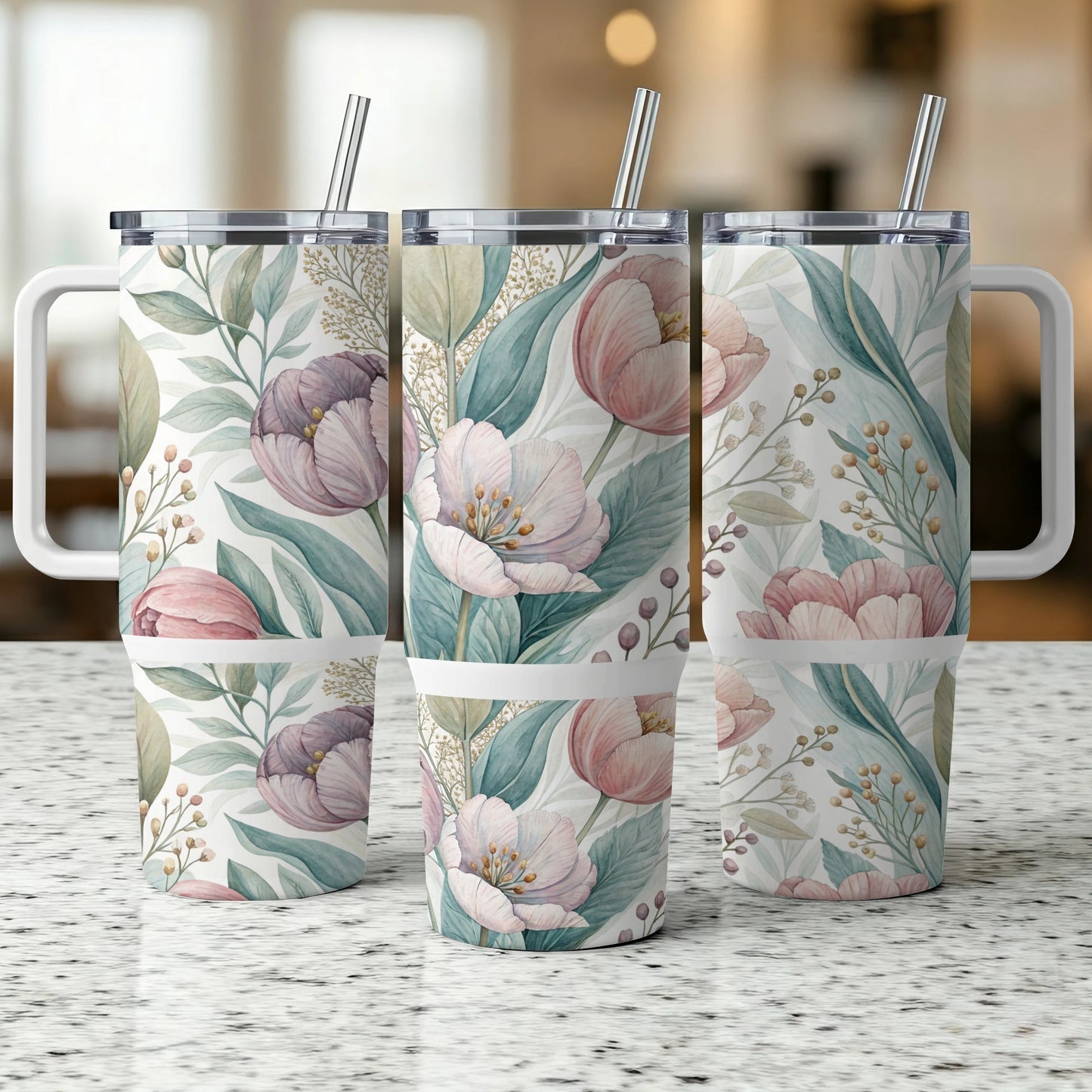 Three floral tumblers with handles and straws on a speckled countertop.