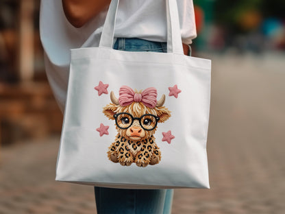 White tote bag with a cartoon Highland cow graphic wearing glasses and a pink bow.