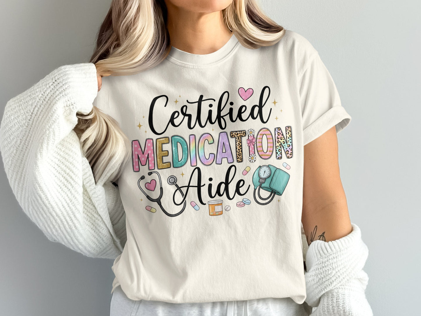 Cream t-shirt with "Certified Medication Aide" text, medical icons, and pastel hearts.